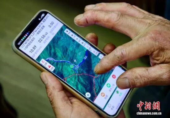 图为5月8日，护林员罗贤华用智能手机上的专业巡护软件填报信息。中新社记者 王东明 摄