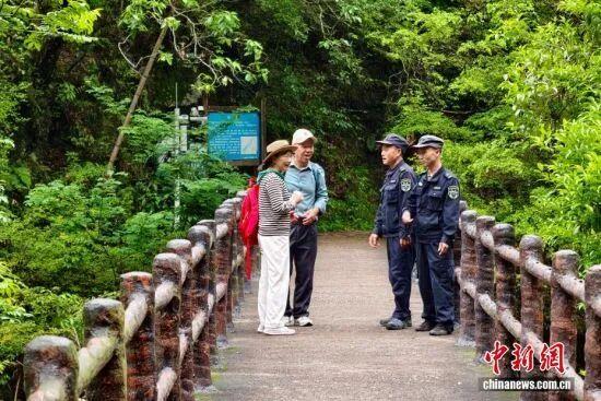 图为5月8日，护林员罗贤华（右二）、季兴发（右一）向游客介绍游览公园安全注意事项。中新社记者 王东明 摄