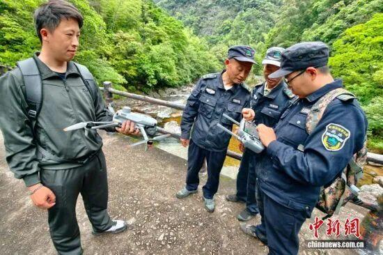 图为5月8日，护林员罗贤华（左二）、季兴发（右二）学习了解巡山无人机设备。中新社记者 王东明 摄